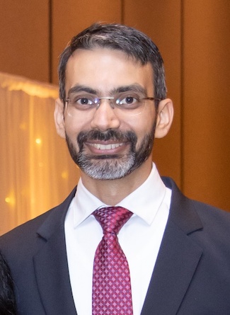 Dr. Paramvir Guram smiling in the office wearing a suit and tie